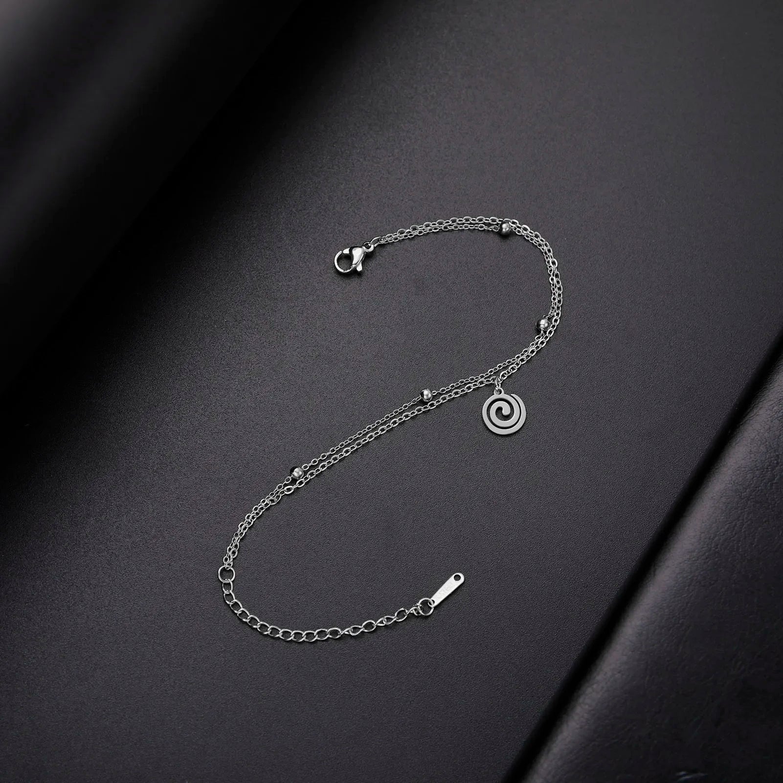 Gold bracelet with small silver spiral charm