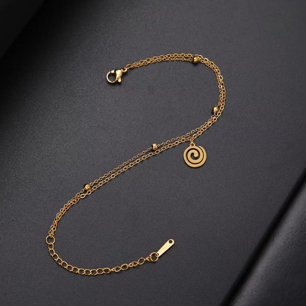 Gold bracelet with small gold spiral charm