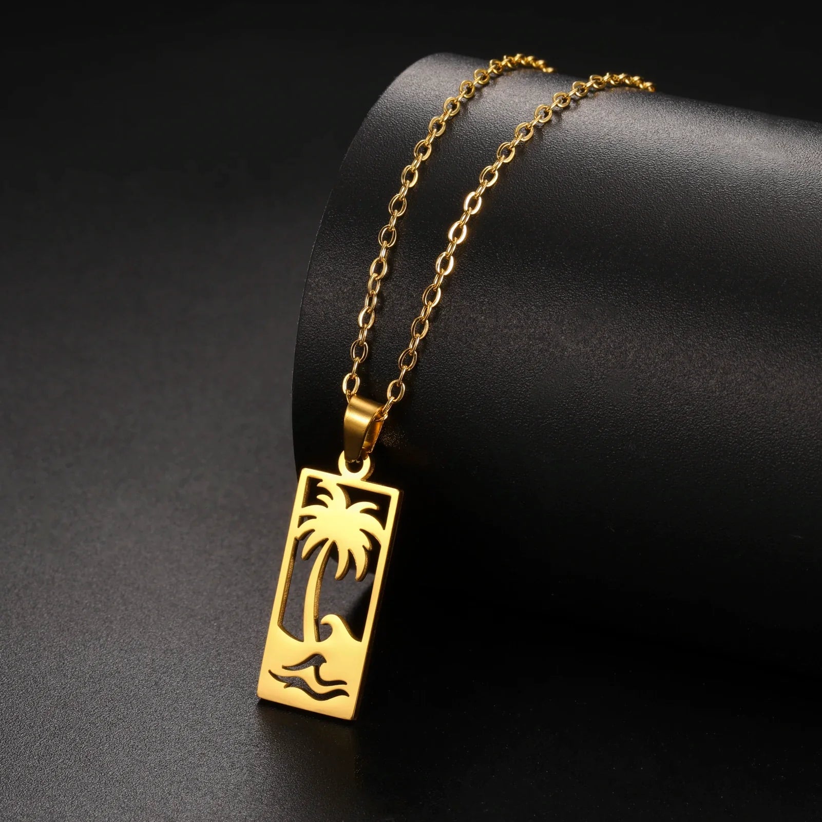 Necklace with palm tree and beach wave pendant in gold
